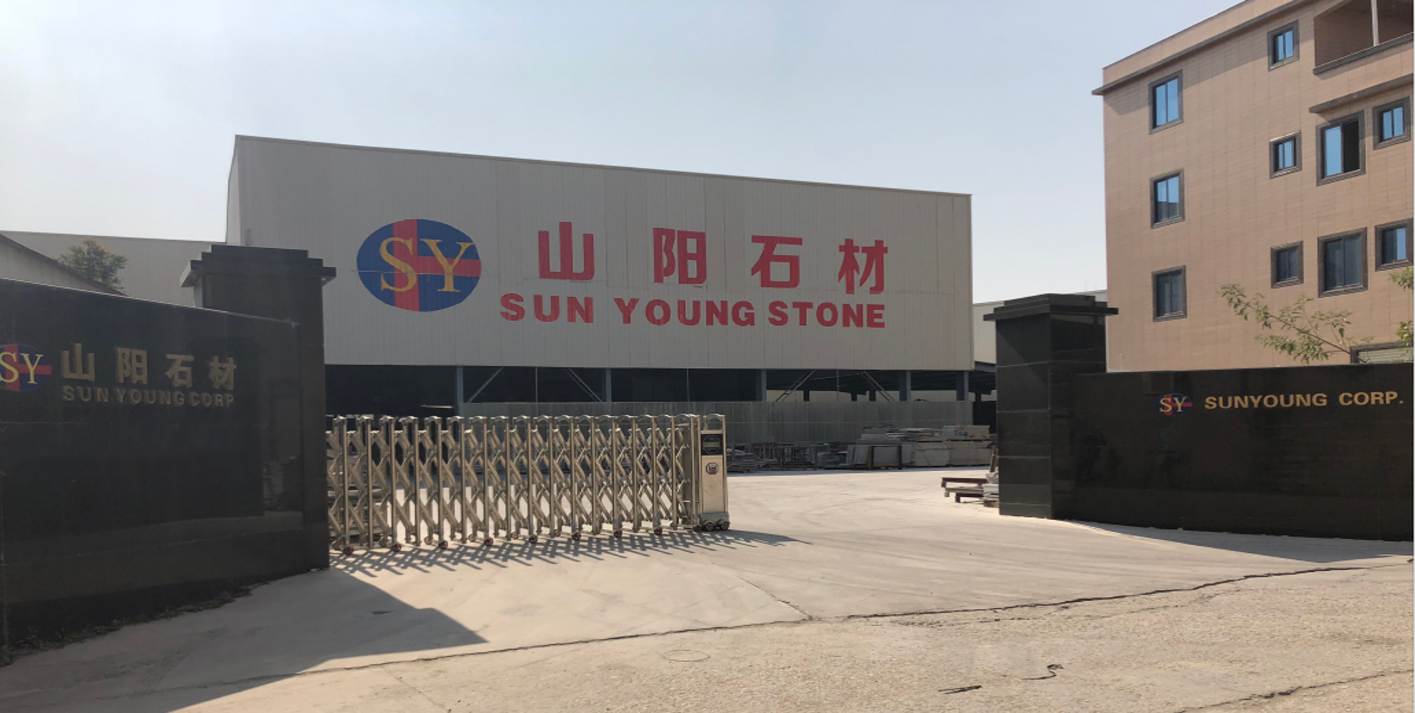 Sun Young Stone processing facility with rows of granite and marble slabs