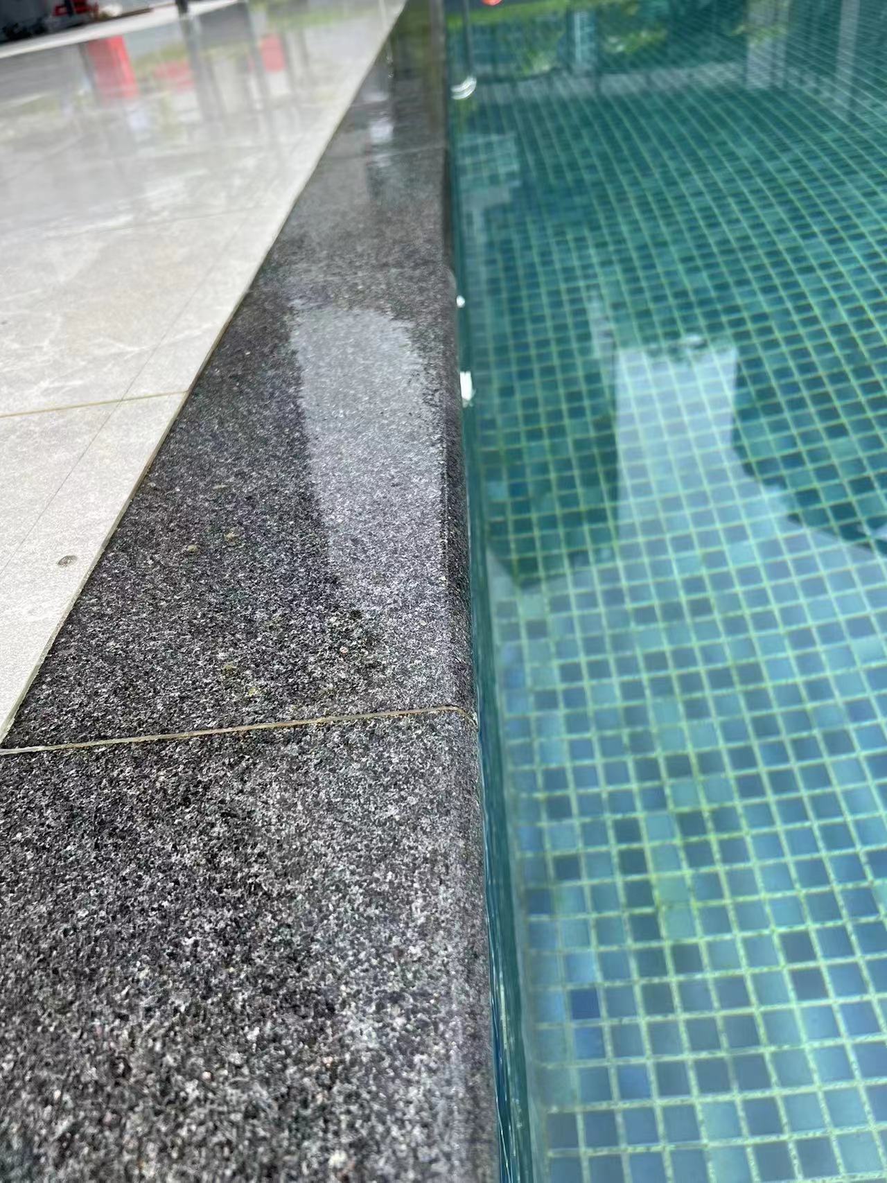 Flamed Black Galaxy granite pool coping beside a glass-tiled swimming pool at the Icon Hotel Singapore