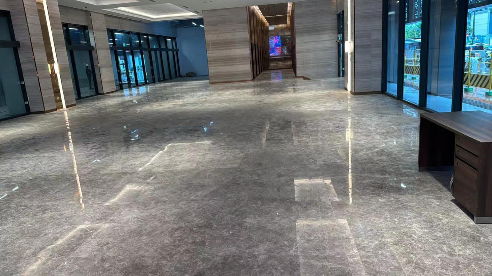 Spacious Icon Hotel Singapore lobby with a large polished Tundra Grey Turkish marble floor and wood-vein marble feature walls