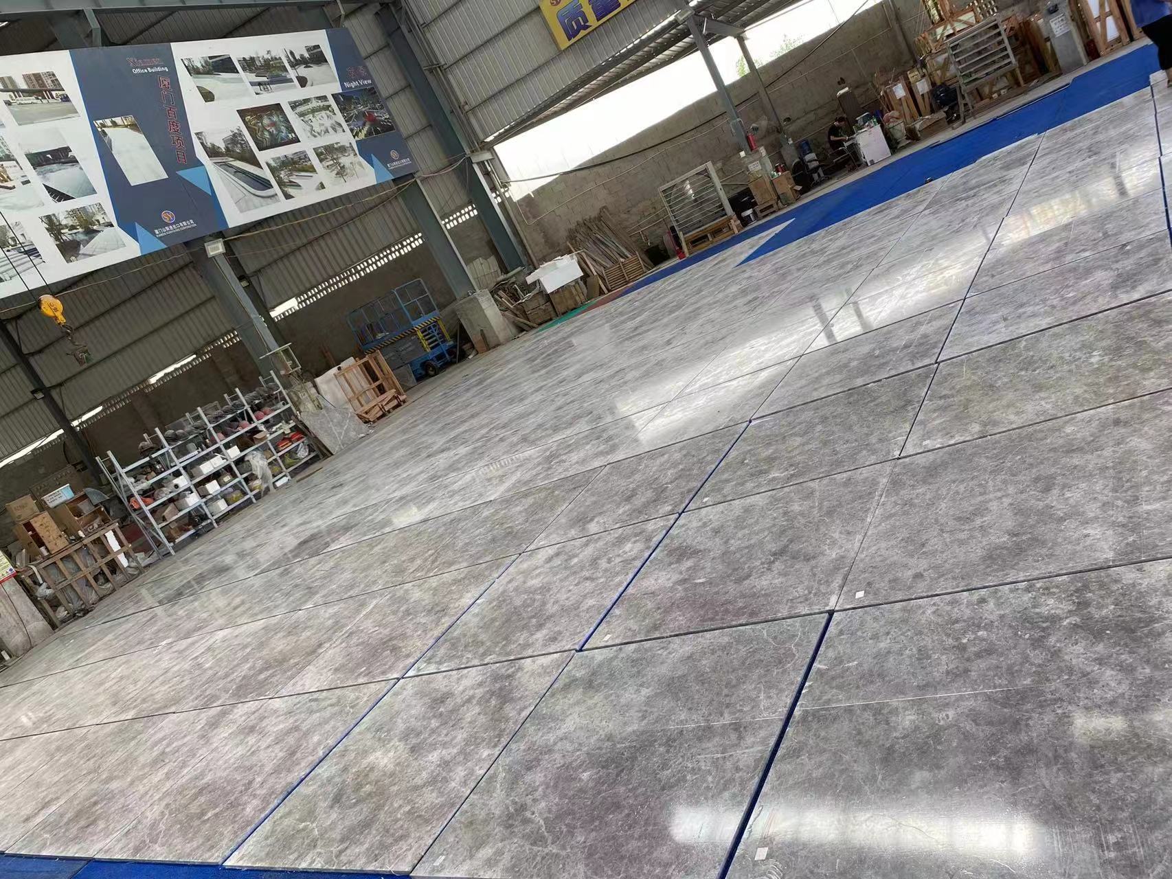 Polished Tundra Grey Turkish marble tiles dry-laid in the factory with slabs stacked along the wall for quality control