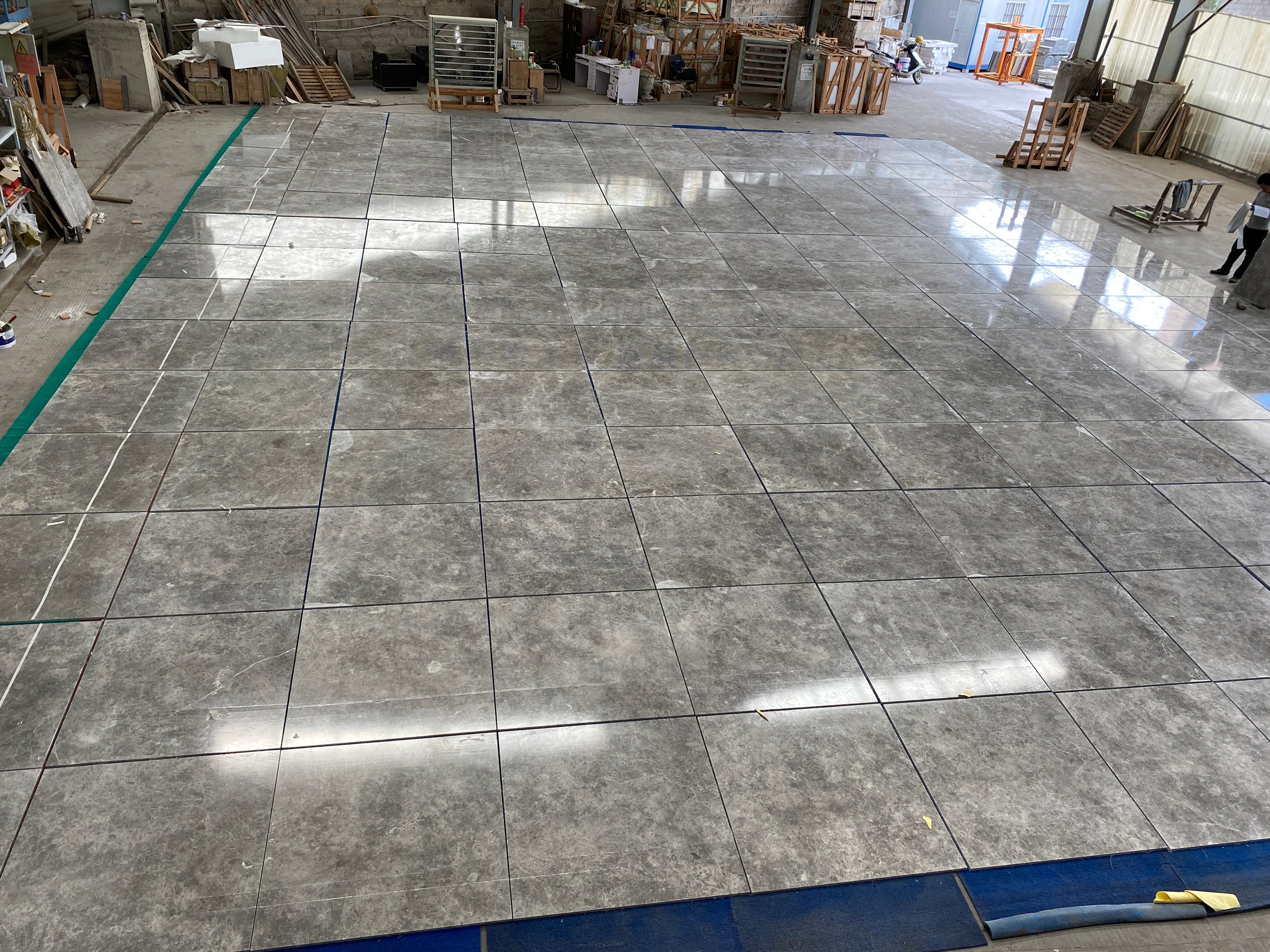 Large field of polished Tundra Grey Turkish marble tiles dry-laid across the factory floor for drying and inspection