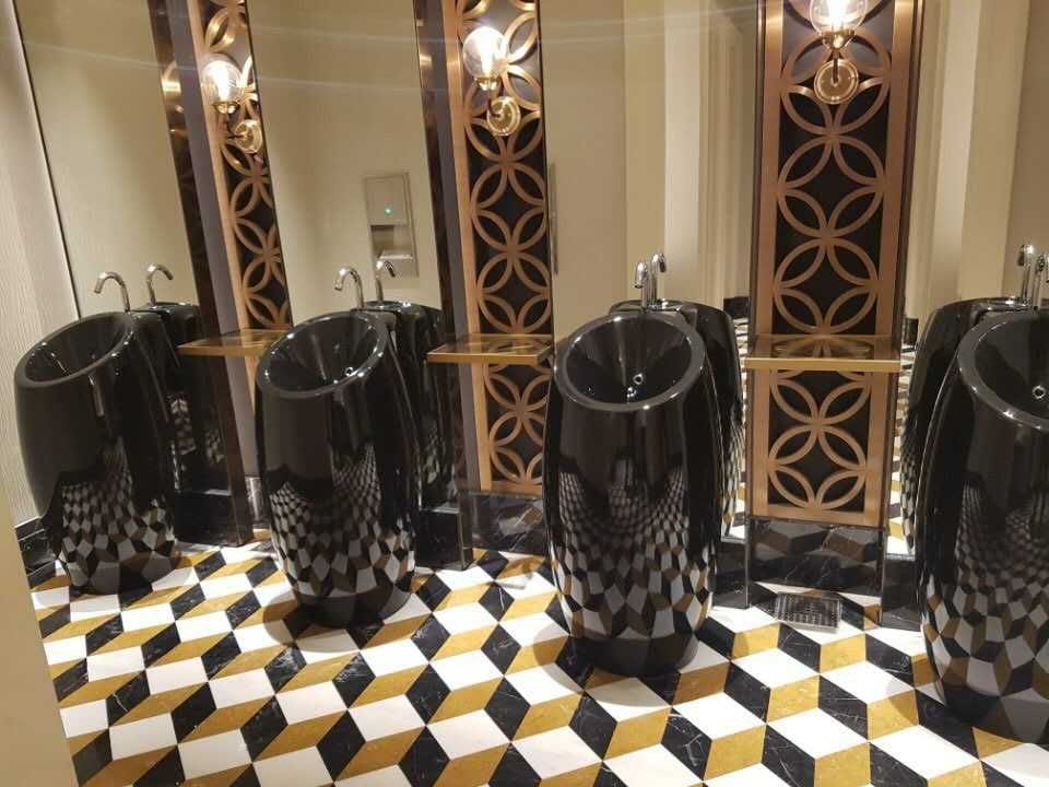 Incheon Casino restroom with 3D cube waterjet marble floor in black, white and brass with black stone fixtures