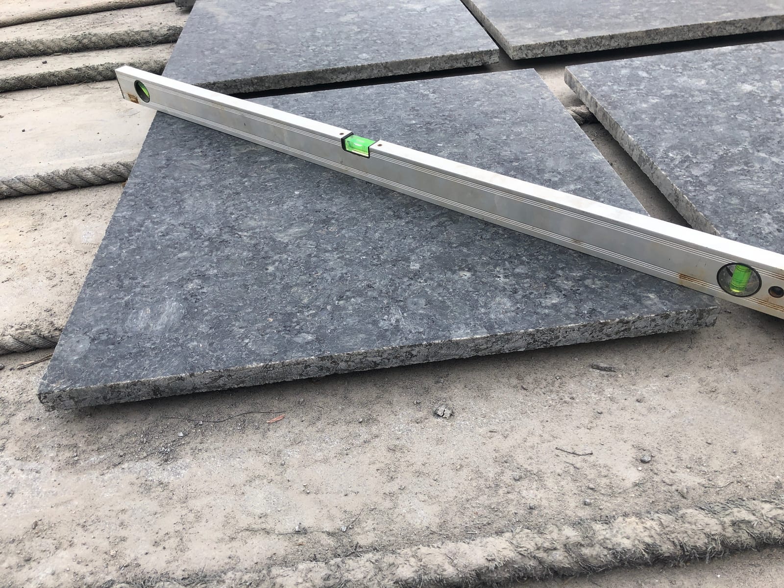Spirit level resting on a polished dark Breton Green granite tile to check flatness