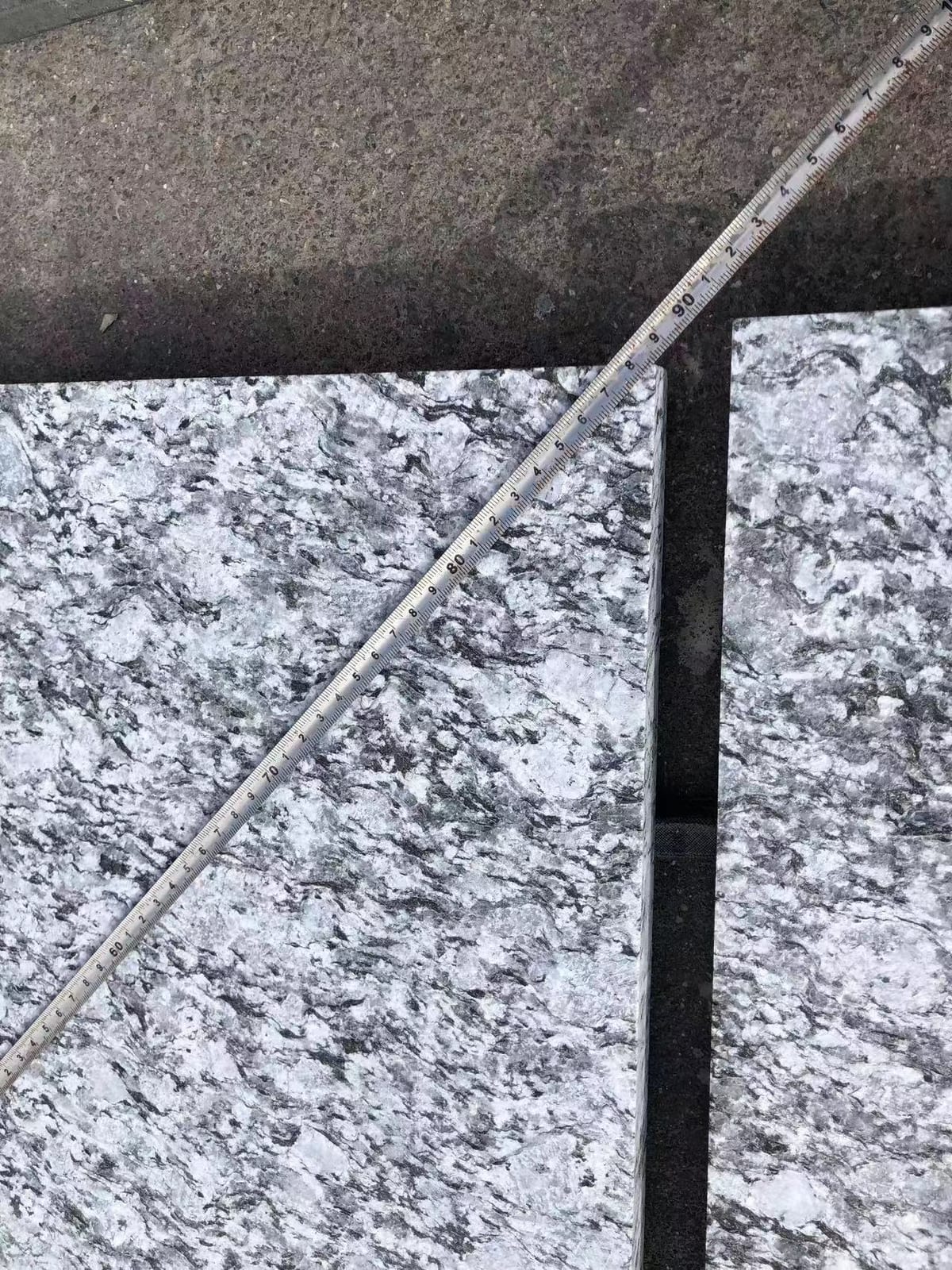 Ruler placed diagonally across sea-wave grey granite tiles to verify dimensions