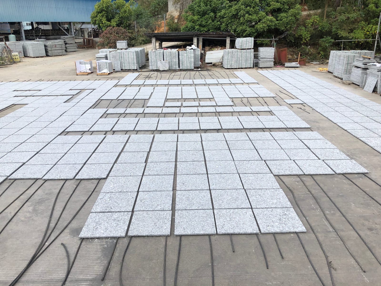 Rows of light sea-wave grey granite tiles drying in the production yard