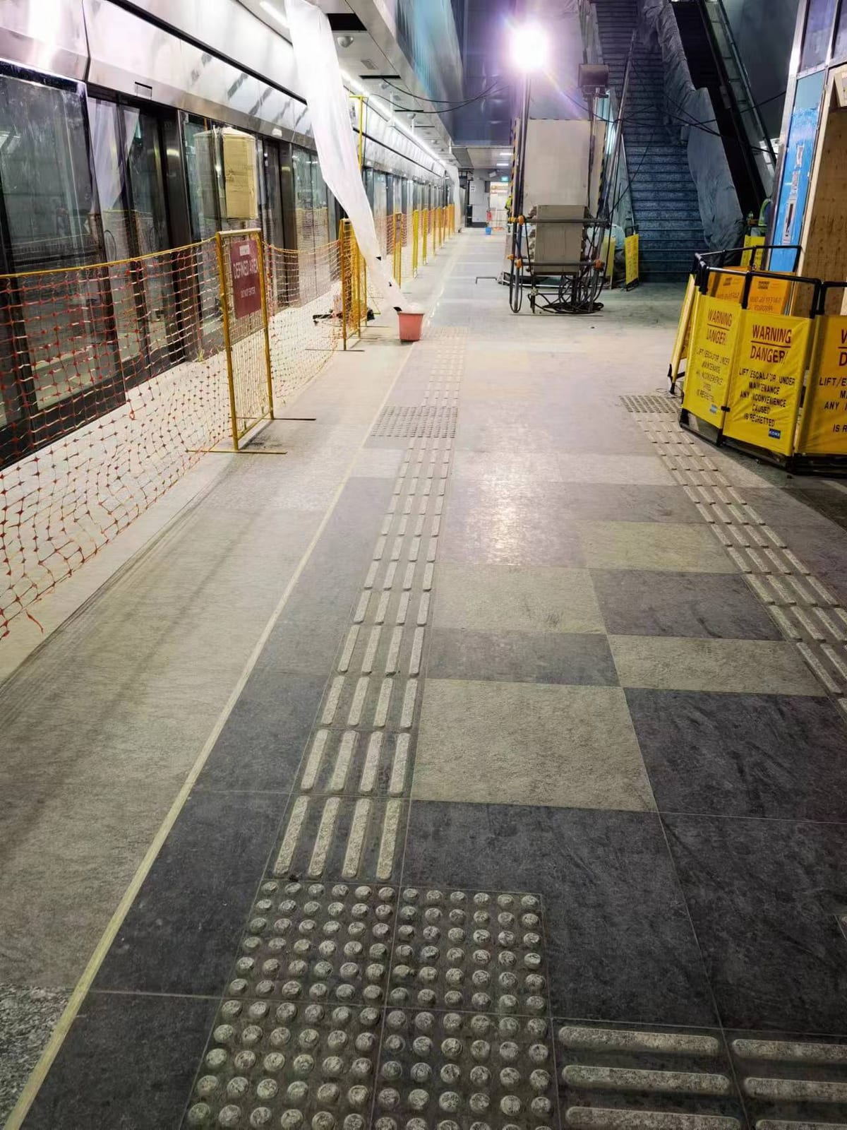 Siglap MRT platform with two-tone grey granite floor paving, tactile guidance paving and a stationary train