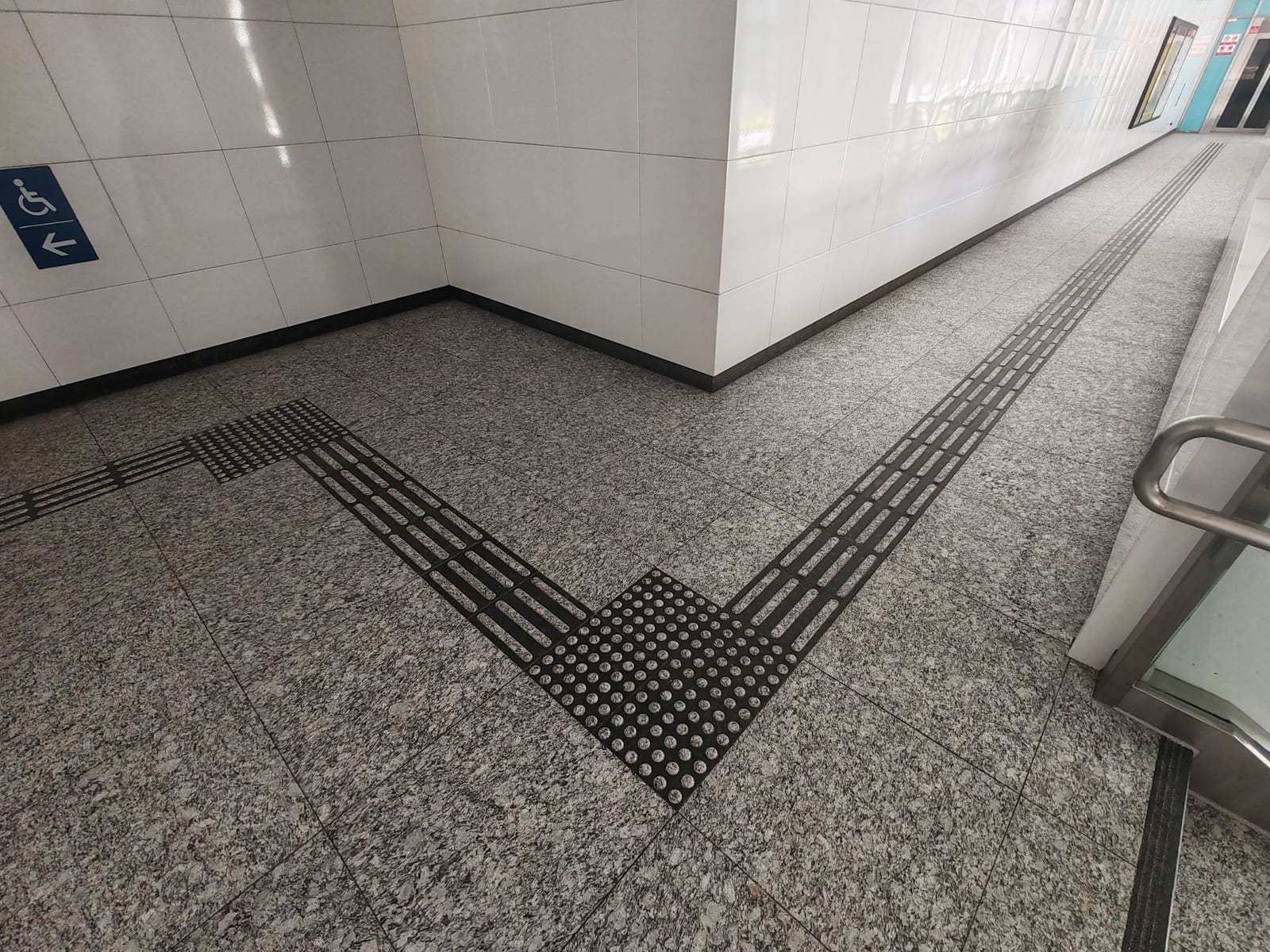 Granite corridor floor at Siglap MRT Station with continuous black directional and warning tactile guidance paving