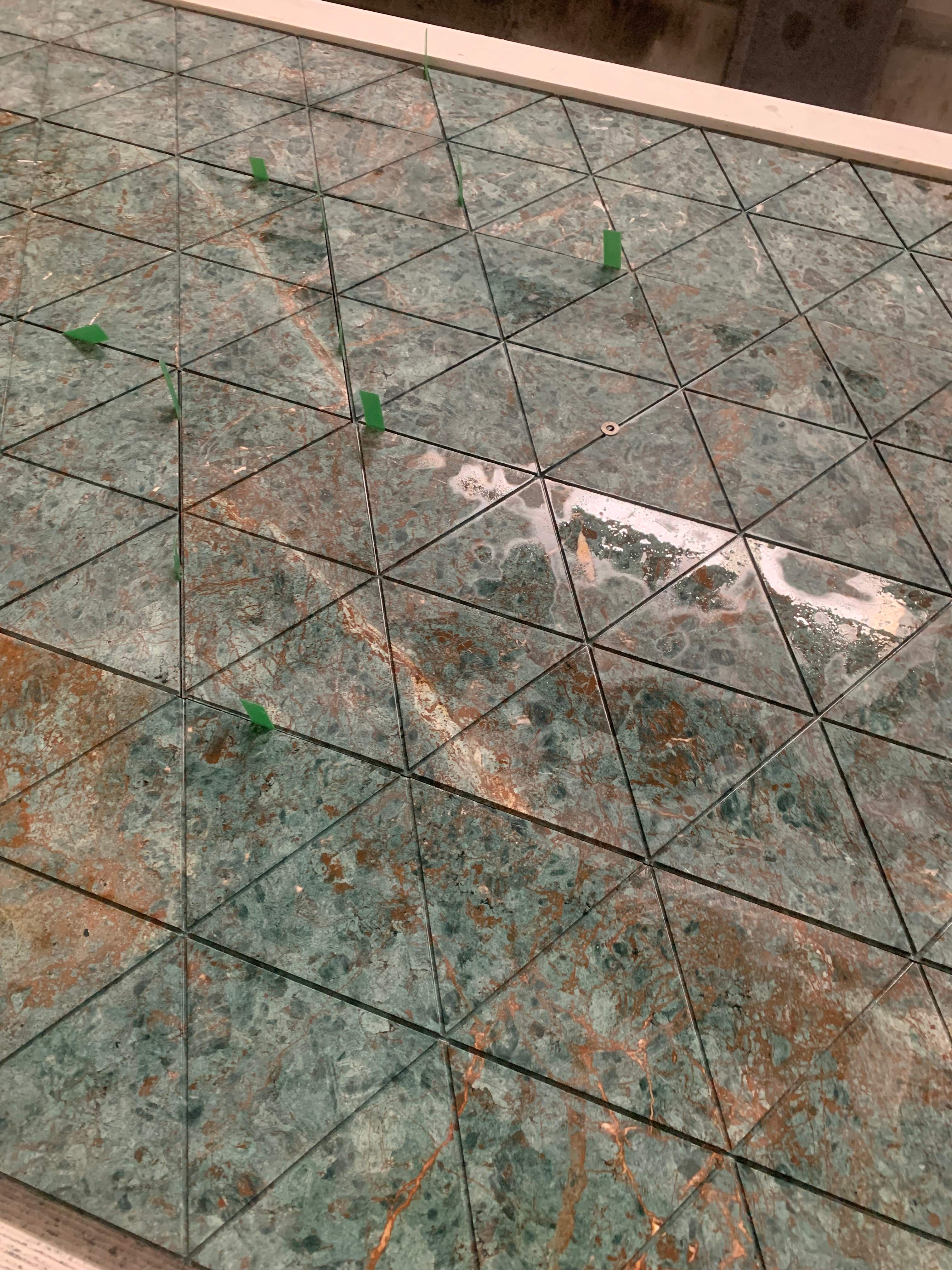 Close-up of triangular fluted Rainforest Green marble tiles with green alignment spacers and matched grooves