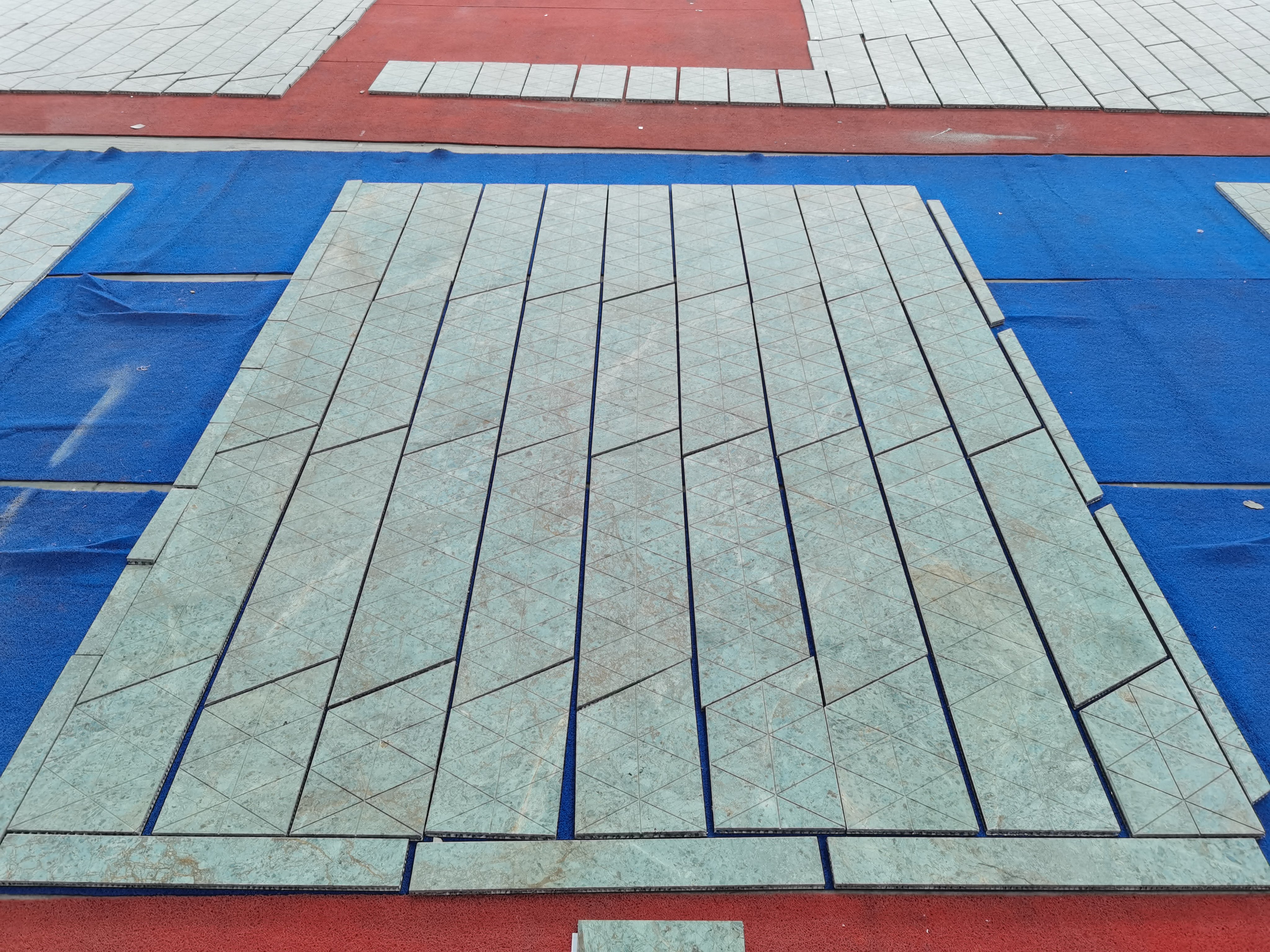 Triangular green marble tiles dry-laid into panels on protective mats