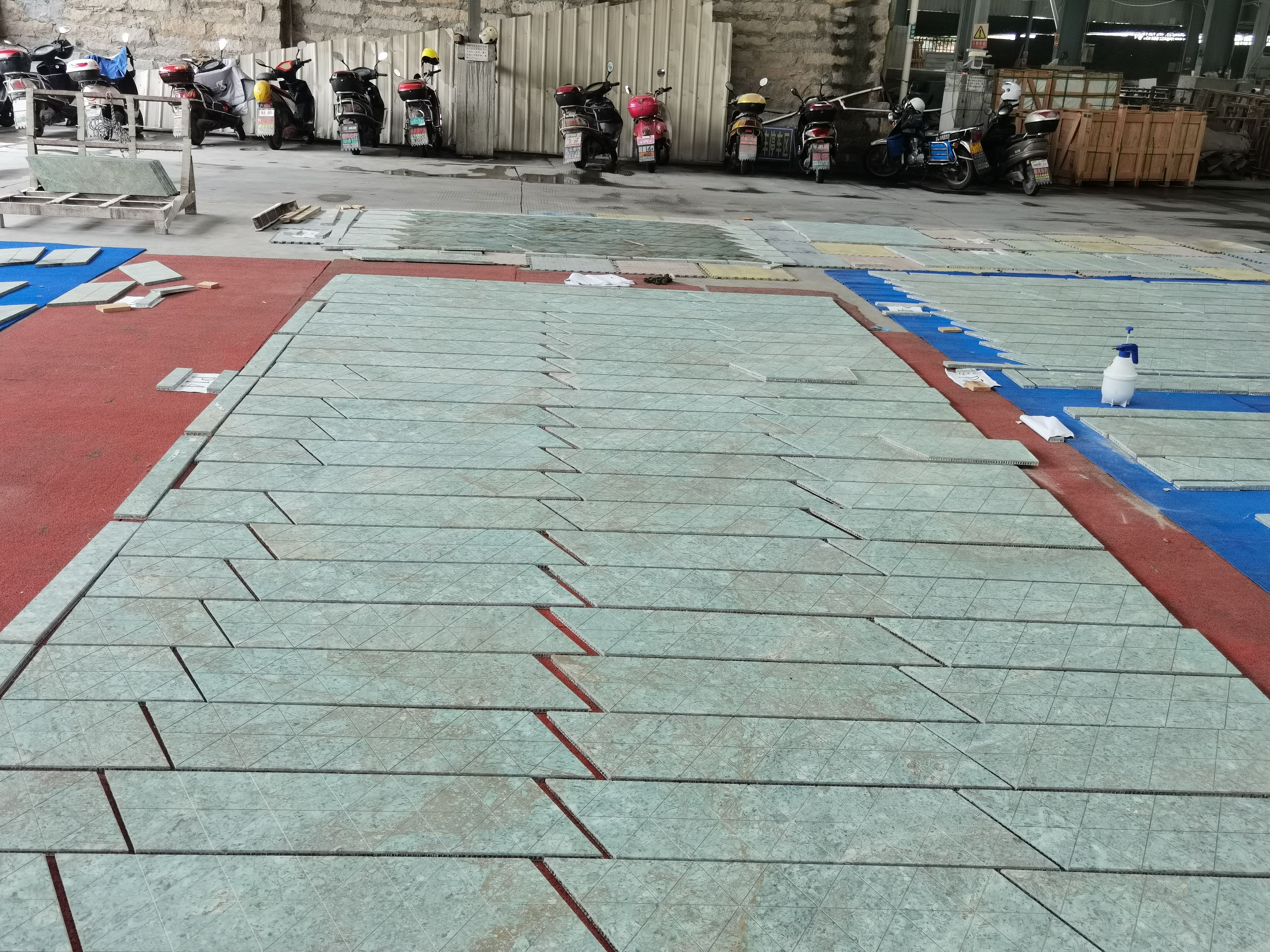 Triangular fluted Rainforest Green marble tiles dry-laid in a herringbone-like field across the factory floor