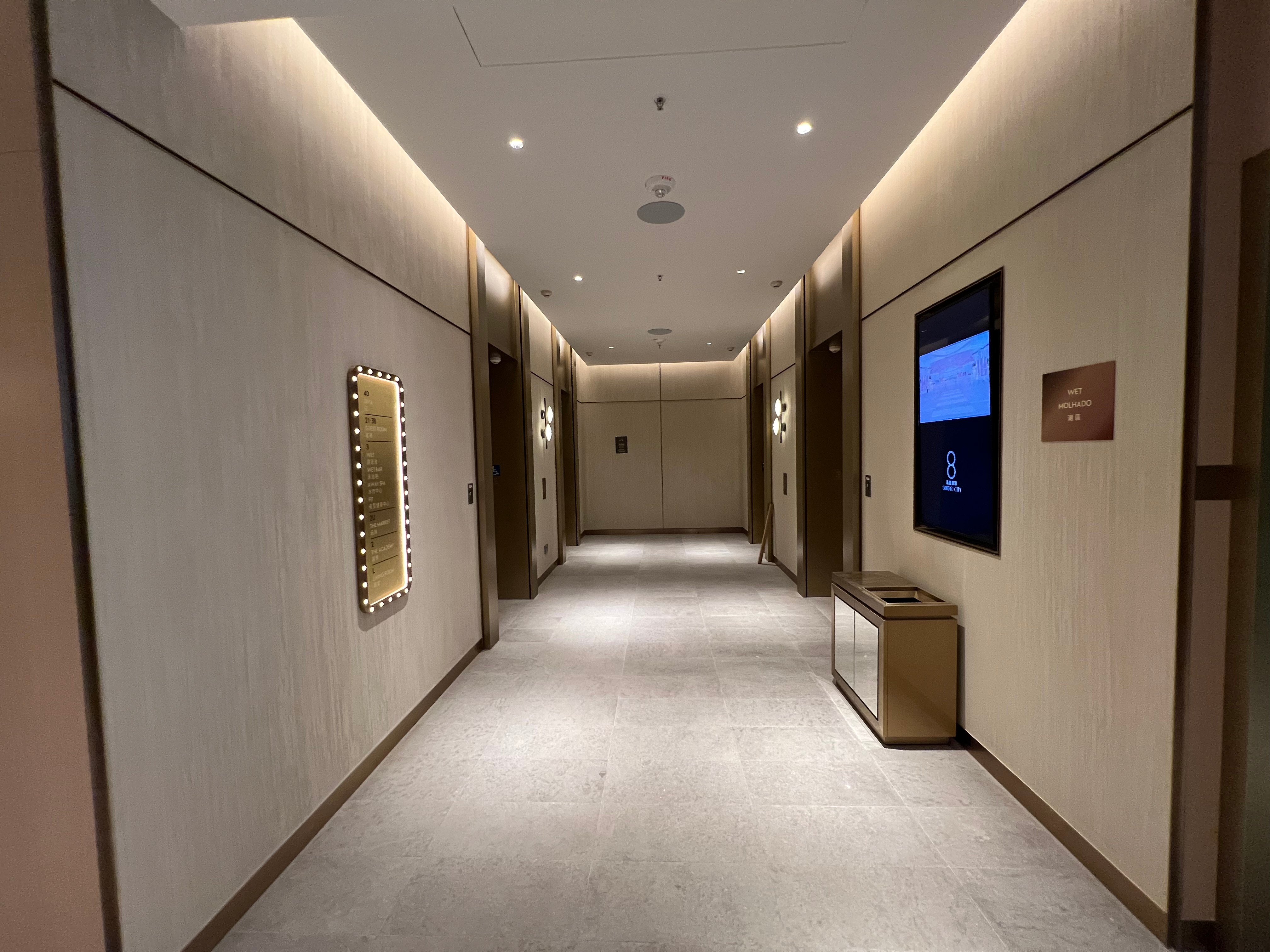 Hotel lift-lobby corridor at Studio City II Macau with warm wood walls and a calibrated stone floor