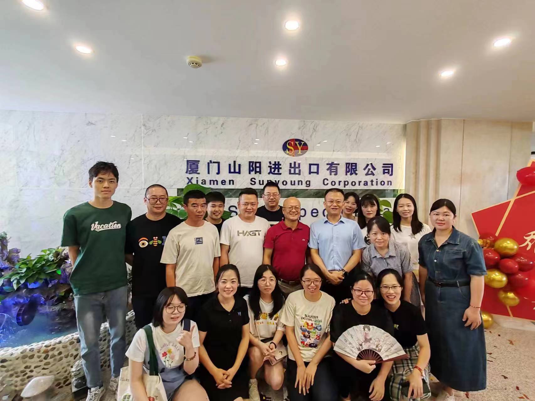 The Xiamen Sun Young Corporation team gathered in front of the company marble signage wall